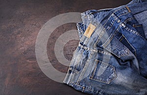 Blue jeans laying on a dark wooden table. Modern fashion jeans - top view with space to copy text