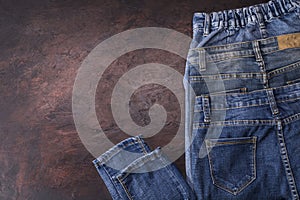 Blue jeans laying on a dark wooden table. Modern fashion jeans - top view with space to copy text