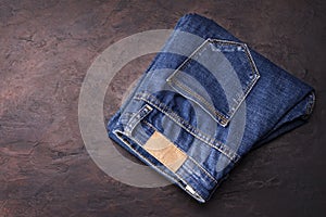 Blue jeans laying on a dark wooden table. Modern fashion jeans - top view with space to copy text