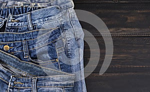 Blue jeans resting on a dark black wooden table. Modern fashion jeans - top view with space to copy text