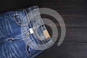 Blue jeans resting on a dark black wooden table. Modern fashion jeans - top view with space to copy text