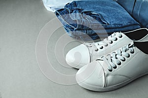 Blue jeans and white sneakers on gray background