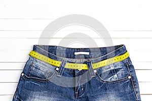 Blue jeans with yellow measure tape instead of belt on white woo