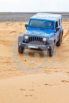 Blue Jeep Wrangler Rubicon Unlimited at desert sand dunes