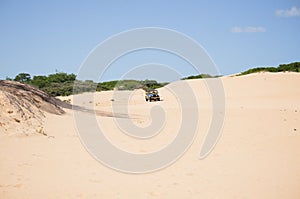 Blue jeep with yellow details driving through beautiful dunes on a beautiful blue sky day