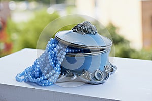 Blue jewelry Box with the silver moldings on the legs, beads a string. Close,