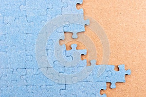 Blue jigsaw puzzle on brown background with copy space. Connected blank puzzle pieces