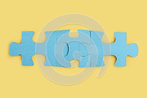 Blue jigsaw puzzle pieces on yellow background. Teamwork  logical thinking. Concept of solutions, mission, success, goals,