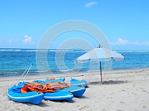 Blue kayaks, orange life jakets and white beach umbrella