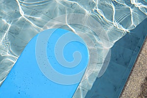 Blue kickboard floating on swimming pool water surface