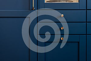Blue kitchen front with round knobs and vertical handle. Elegant detail.