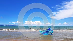 Blue kite surfing falling down on the pattaya beach with sea, cloud and clear blue sky background with copy space