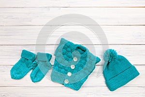 Blue knitted clothes for baby on white wooden background