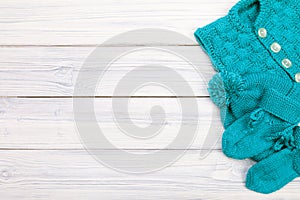 Blue knitted clothes for baby on white wooden background