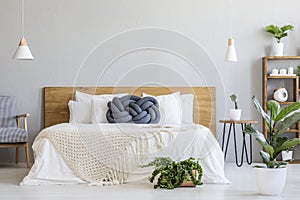 Blue knot pillow on bed with wooden headboard in grey bedroom in