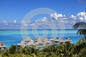 Blue lagoon of the Bora Bora island, Polynesia. Top view on palm trees, traditional lodges over water and the sea