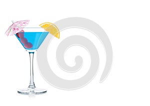 Blue lagoon cocktail in martini glass with orange slice and sweet cherry with umbrella on white