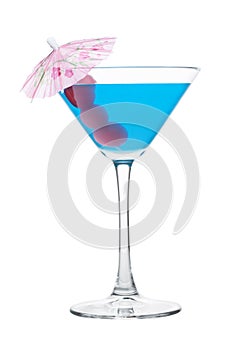 Blue lagoon cocktail in martini glass with sweet cherry and umbrella on white