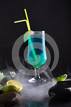 Blue Lagoon cocktail with a slice of lime in an elegant glass on a black background. Vertical photo.