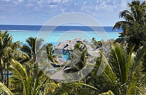 Blue lagoon of the island of Bora Bora, Polynesia. A view from height on palm trees, traditional lodges over water and the sea