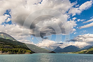Blue lake amid mountain range and dramatic sky in idyllic uncontaminated environment once covered by glaciers. Dramatic sky