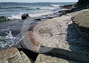 Blue Lake Champlain waves over grey and oxidized chazy limestone photo