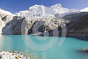 Blue lake in foot of snow-covered mountain at sunrise