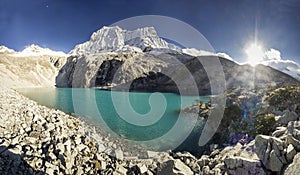 Blue lake in foot of snow-covered mountain at sunrise