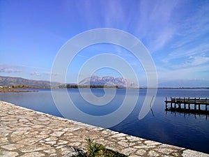 Blue lake of Mesologi, Aetolia Acarnania, Greece on a misty day. View of the pier for fishing boats.