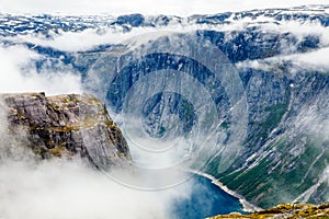 Blue lake surrounded by steep cliffs hiding in clouds, Odda, Hordaland county, Norway