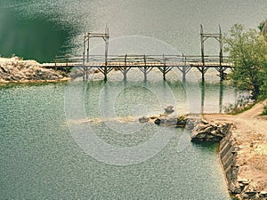 Blue lake with wooden tourist path bridge above cold water