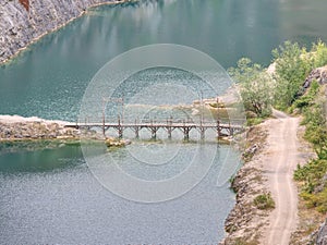 Blue lake with wooden tourist path bridge above cold water