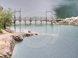Blue lake with wooden tourist path bridge above cold water