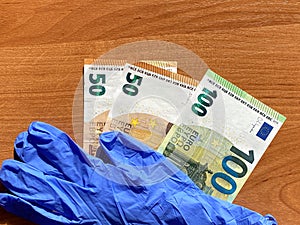 Blue latex gloves and 50 and 100 euro bills. For the cashier or seller, sale. The bottom of the picture