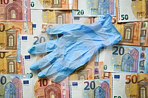 Blue latex surgical glove laying on the  European union money currency Euro