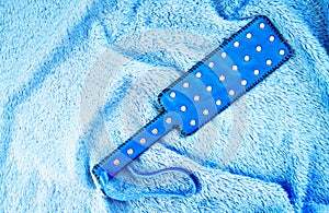 Blue leather slap on bed. Accessories for adult sexual games. Toys for BDSM, spanking devices. Spanking and punishment concept.