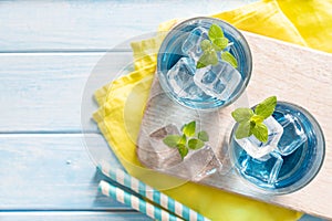 Blue lemonade in glasses on wood background