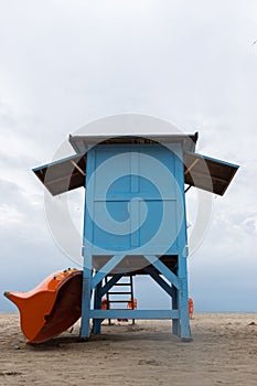 A blue lifeguard booth on the beach on a cloudy day.