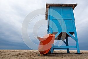 A blue lifeguard booth on the beach on a cloudy day.