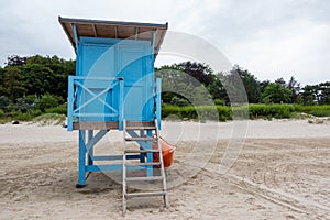 A blue lifeguard booth on the beach on a cloudy day.