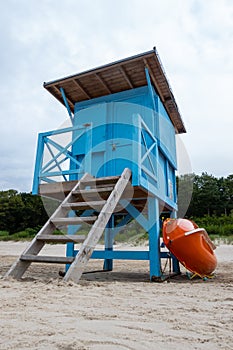 A blue lifeguard booth on the beach on a cloudy day.