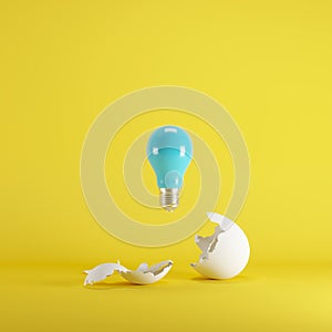 Blue light bulb floating from white eggshell on yellow background.