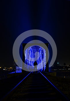 Blue light illuminated train bridge and a man