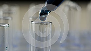 Blue liquid drops from pipette into testing tube