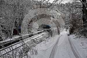 Blue local train arriving through a snowy forest