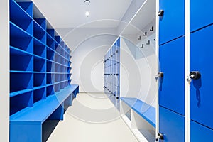 Blue lockers and cabinet with empty shelves and bench