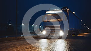 Blue Long Haul Semi-Truck with Cargo Trailer Full of Goods Travels At Night on the Freeway Road