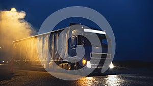 Blue Long Haul Semi-Truck with Cargo Trailer Full of Goods Travels At Night , Turning on Freeway