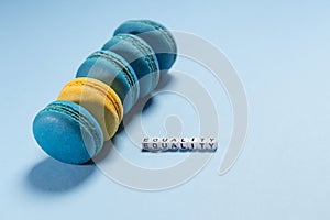 Blue macaroons and yellow macaroon and letters with the word equality