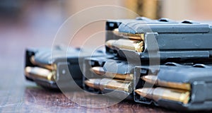 Magazines with bullets of firearm putted on wooden table. Close up view, blurred background.